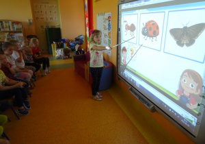 Dziewczynka wskazuje biedronkę z pośród innych zwierząt na tablicy interaktywnej.